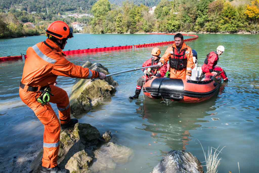 Rescue professional pulling a boat with other rescue professionals in a flooded area