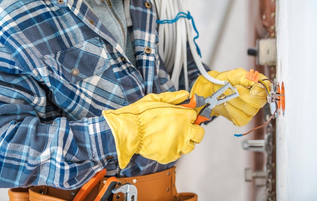 Electrician wearing gloves and installing lighting point inside a wall