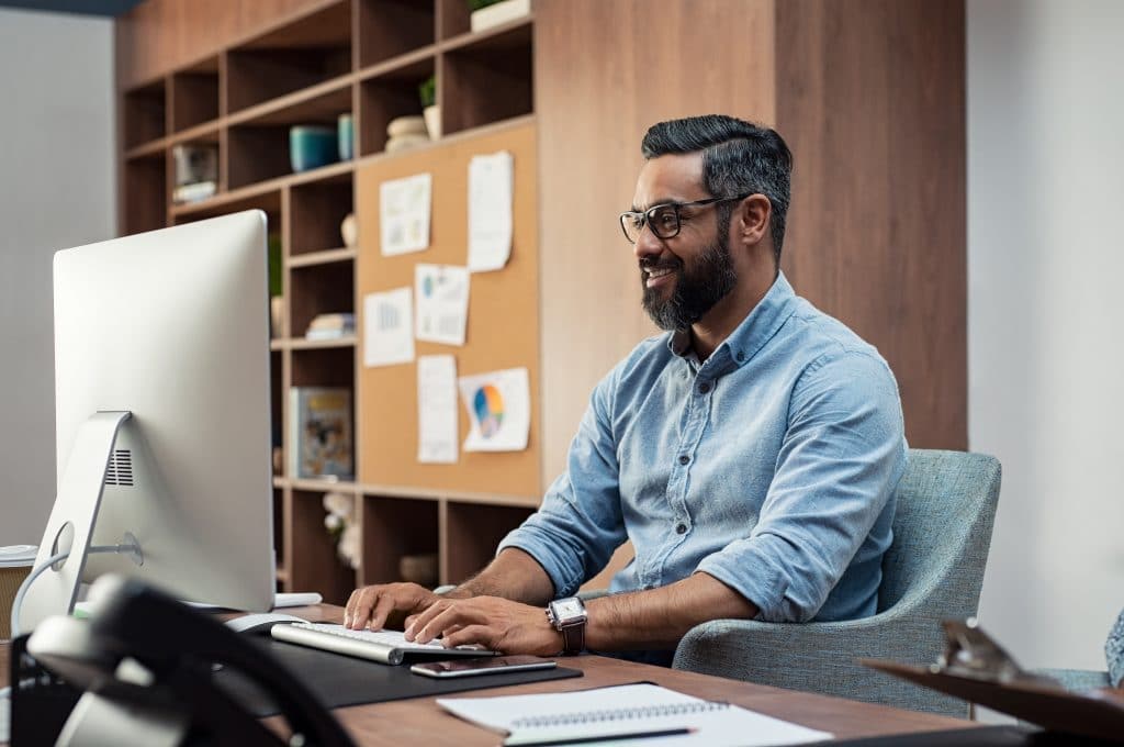 Middle-aged man sitting a desktop computer in a tidy office area