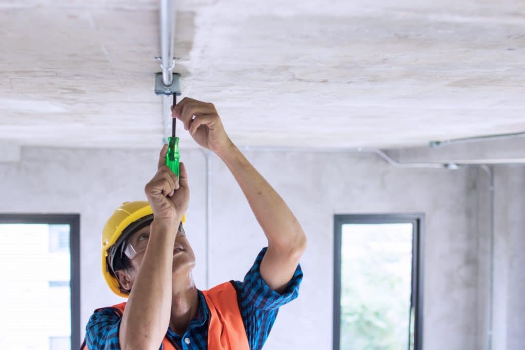 Electrician installing lighting technology with a wrench inside a building