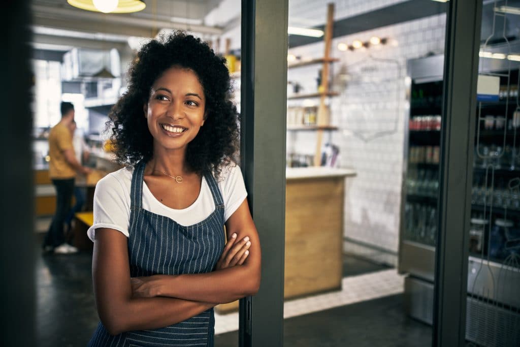 Smiling business owner standing inside franchised food service business