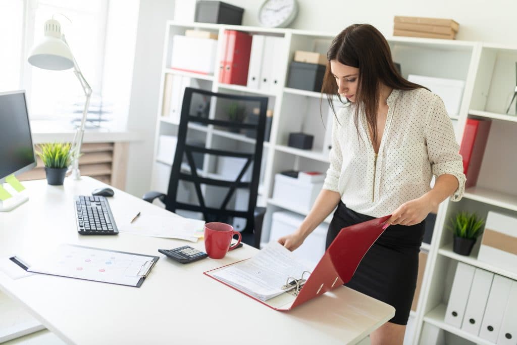 Business woman reviewing notes inside a binder in her an office