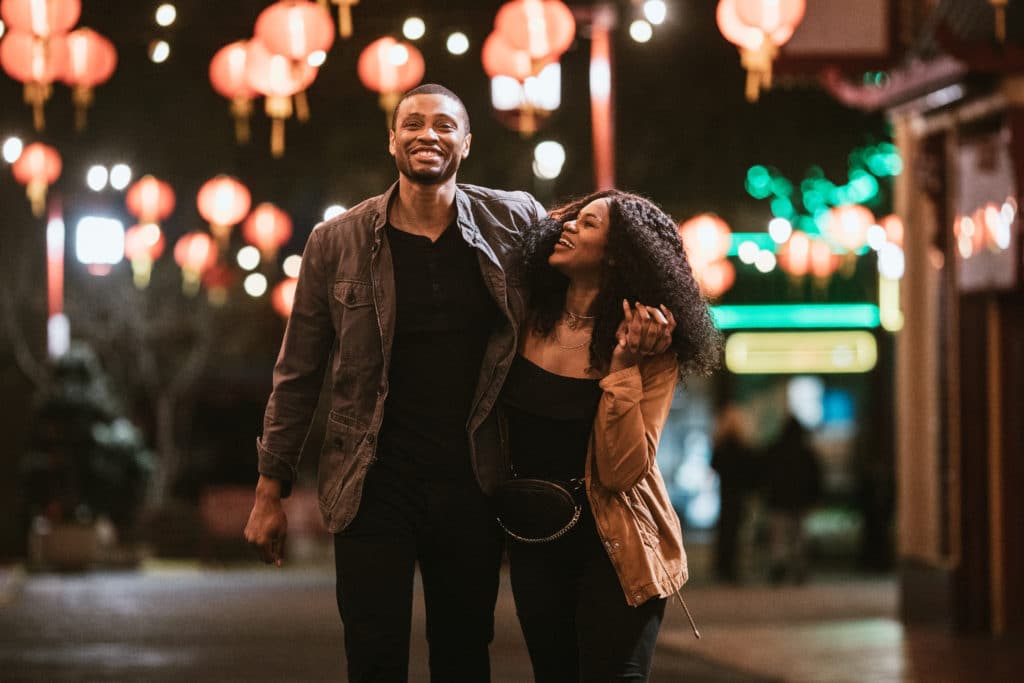 A smiling man and woman walk arm in arm on the streets of Chinatown in L.A. California 