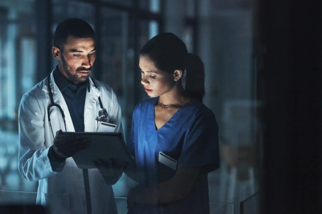 Two medical professionals reviewing emergency preparedness plans on a tablet.