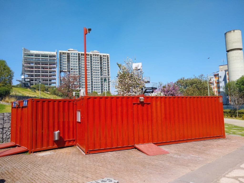 Two large red shipping containers sitting on the ground at a park