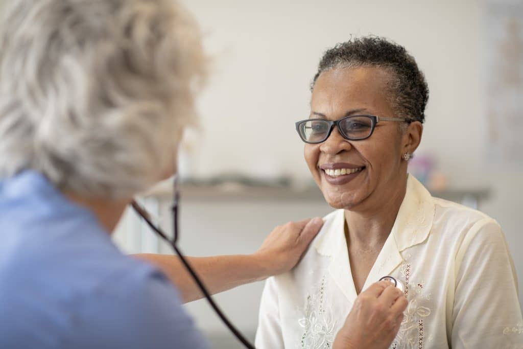 A female doctor checking the heartbeat of a female senior patient