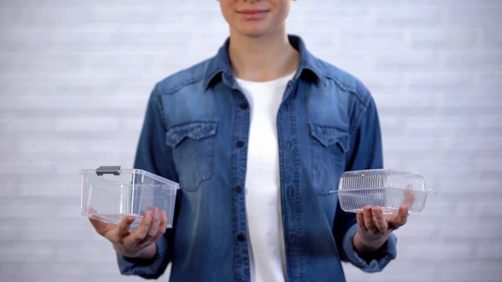Person holding a reusable container in right hand and plastic container in left hand