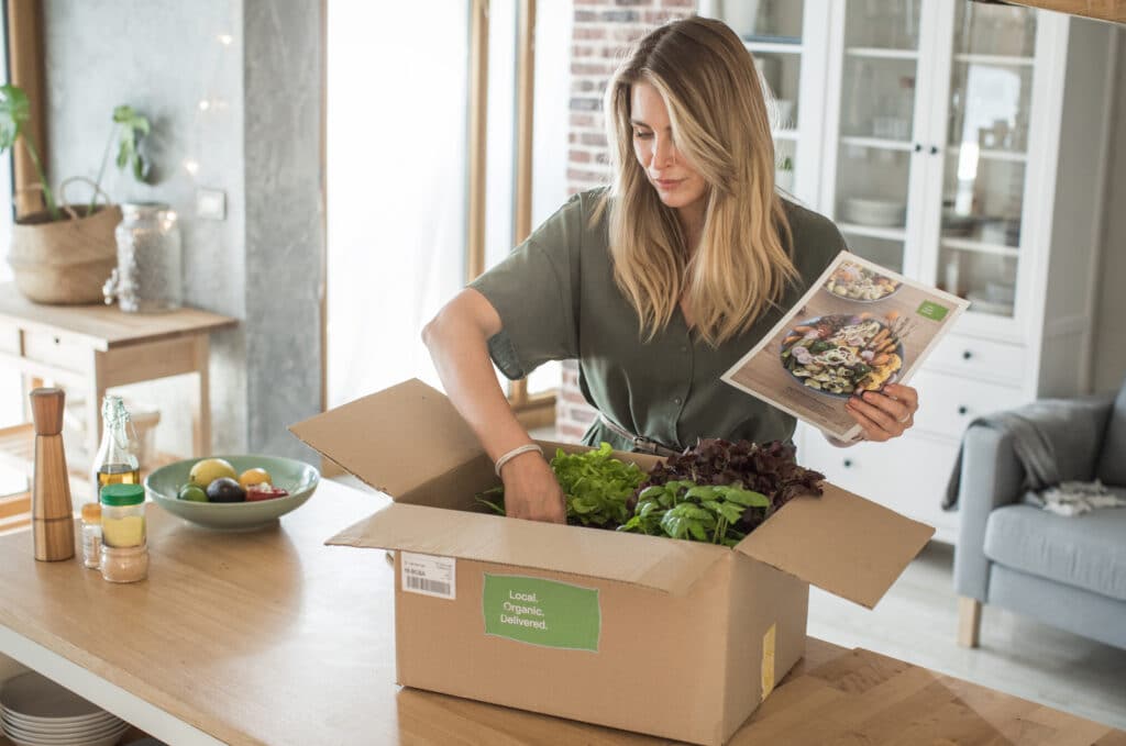 Woman is received box loaded with organic vegetables from delivery service