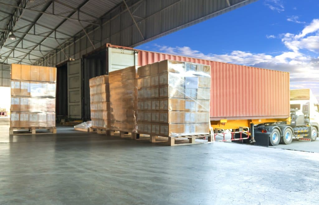 A truck docked at a warehouse with shipments being unloaded