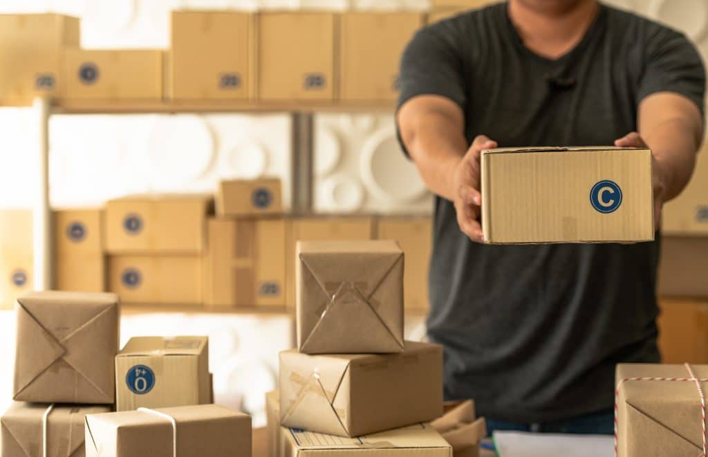 A man holding up a wrapped package for shipping