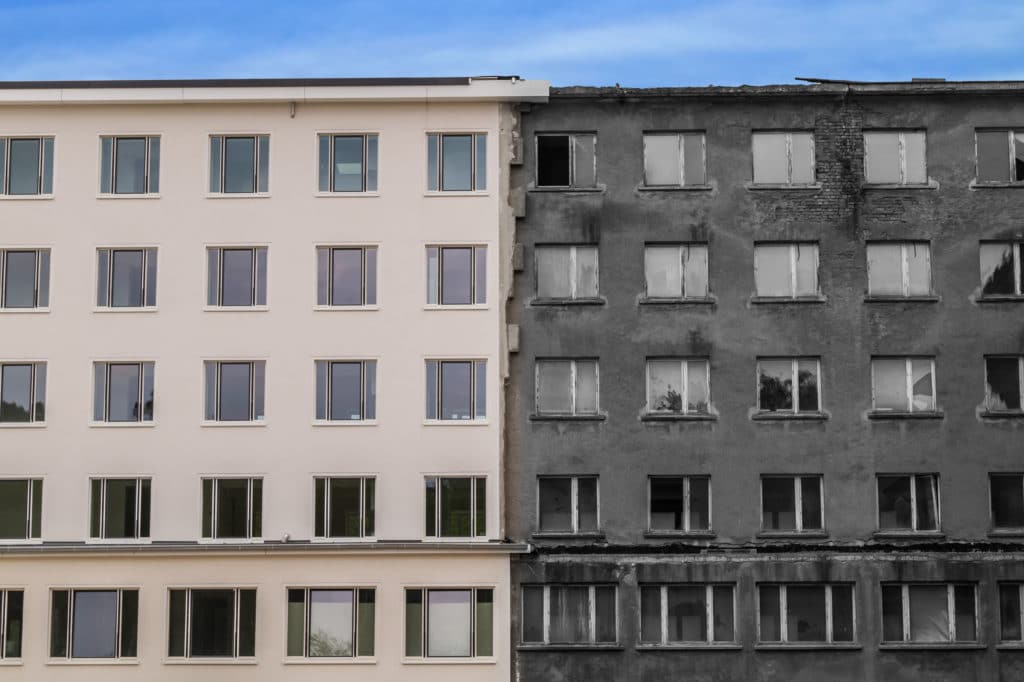 A restored multi-level building standing next to a damaged multi-level building