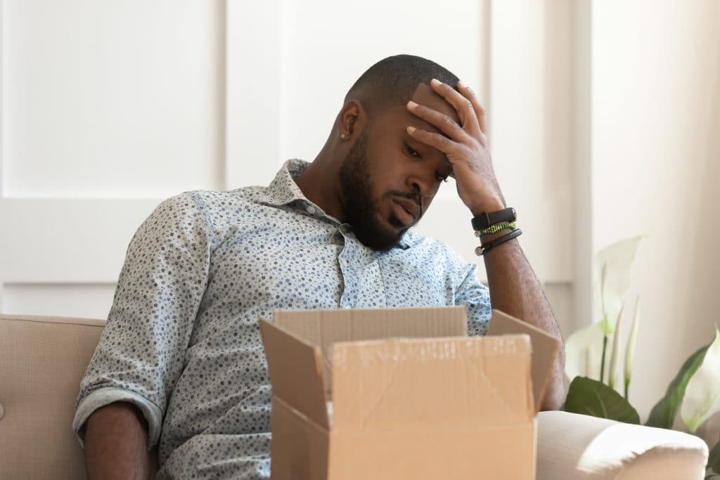 Man inside home unhappy looking at the contents within his opened delivery box