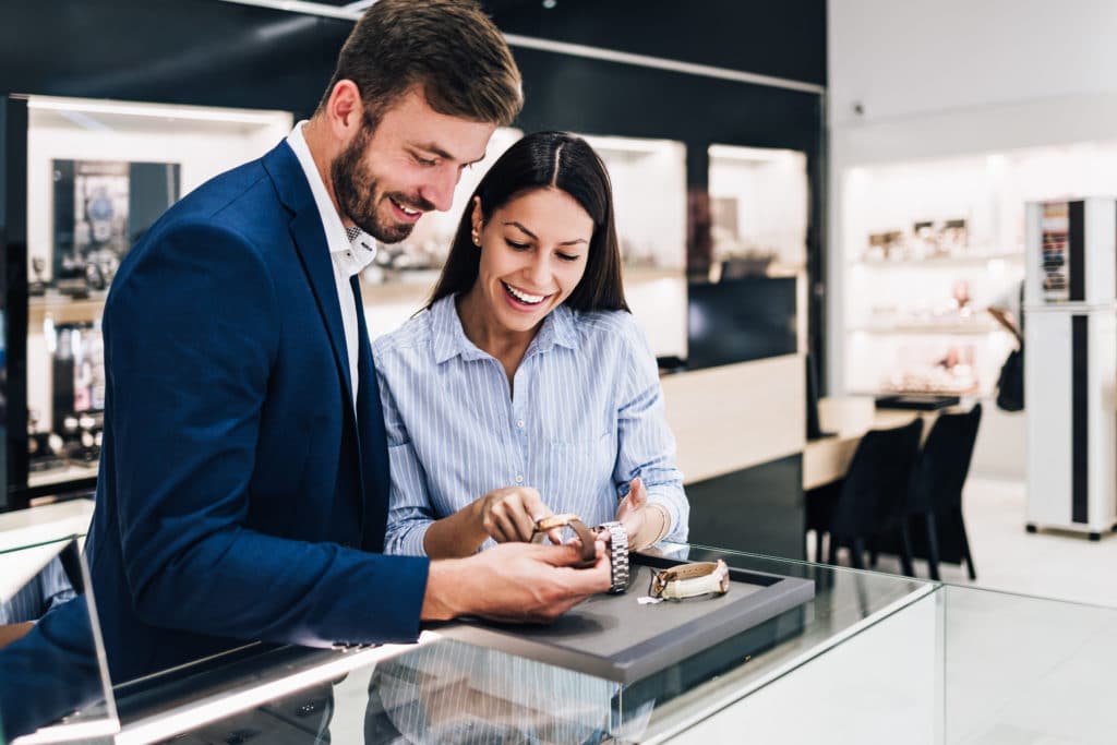 Man and woman looking a watches at a counter inside a store