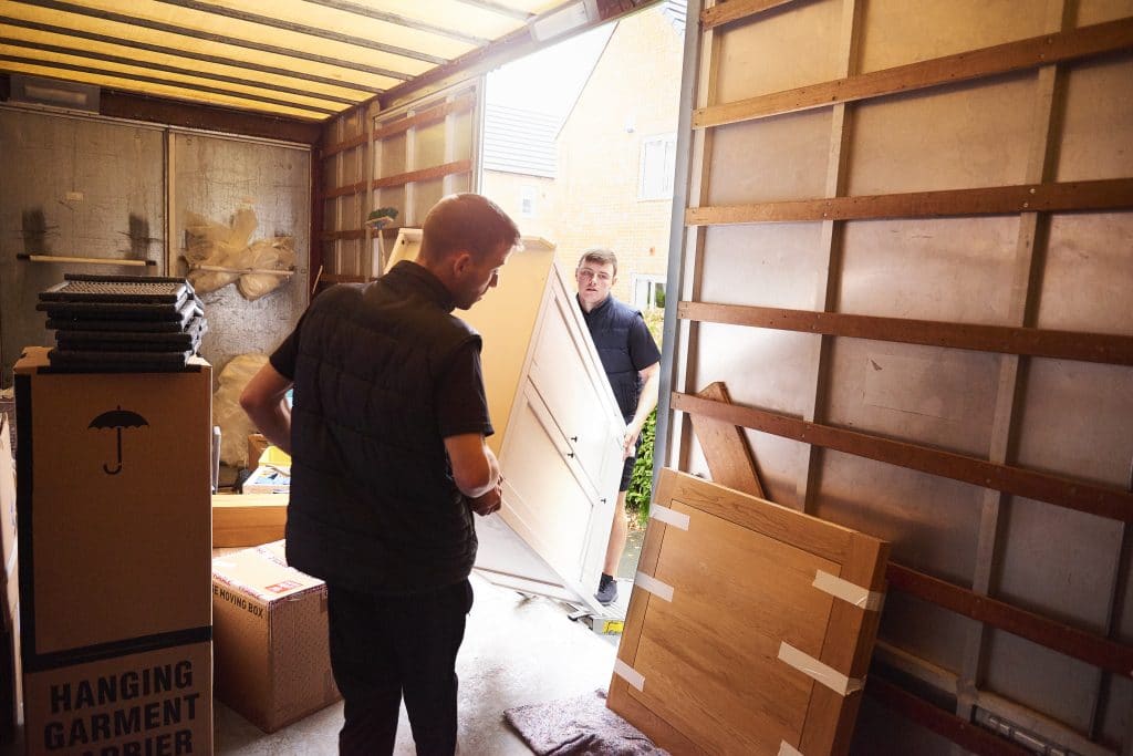 Commercial movers lifting a piece of furniture into a moving truck
