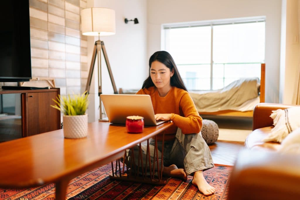 Young woman working on a laptop inside a bedroom