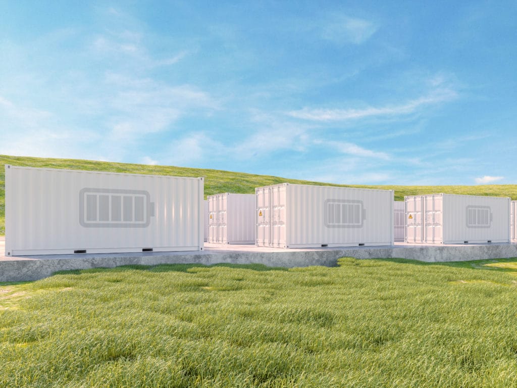Multiple shipping containers in a meadow being used for green energy storage