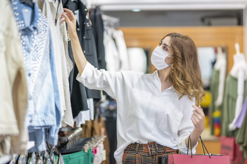 Woman wearing face mask while browsing clothes inside a store
