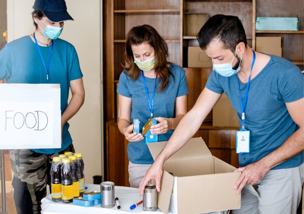 Volunteers wearing face masks while packing boxes with food for flood disaster preparedness