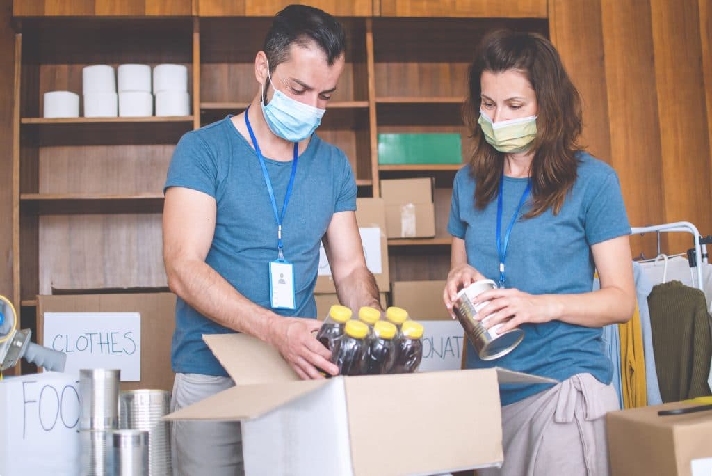 Nonprofit volunteers packing boxes with donations while wearing facemasks