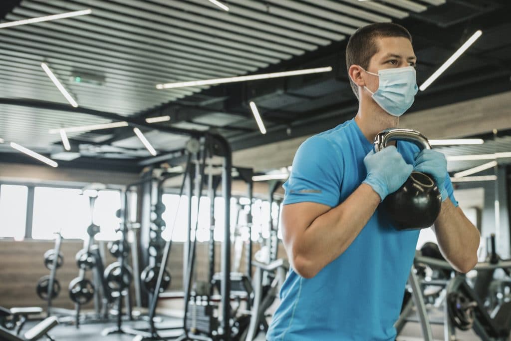 Athlete training inside a gym while wearing a face mask