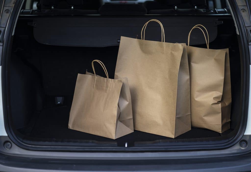Shopping bags from curbside pick up sitting inside a car trunk