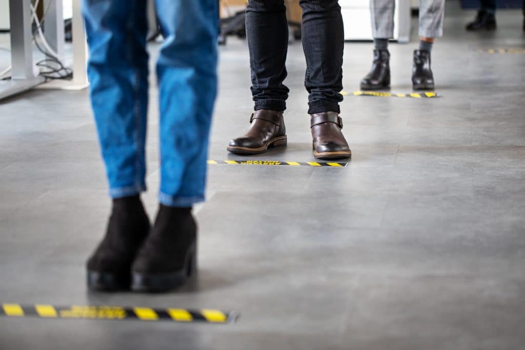 Long line of peoples feet standing behind ground markers 