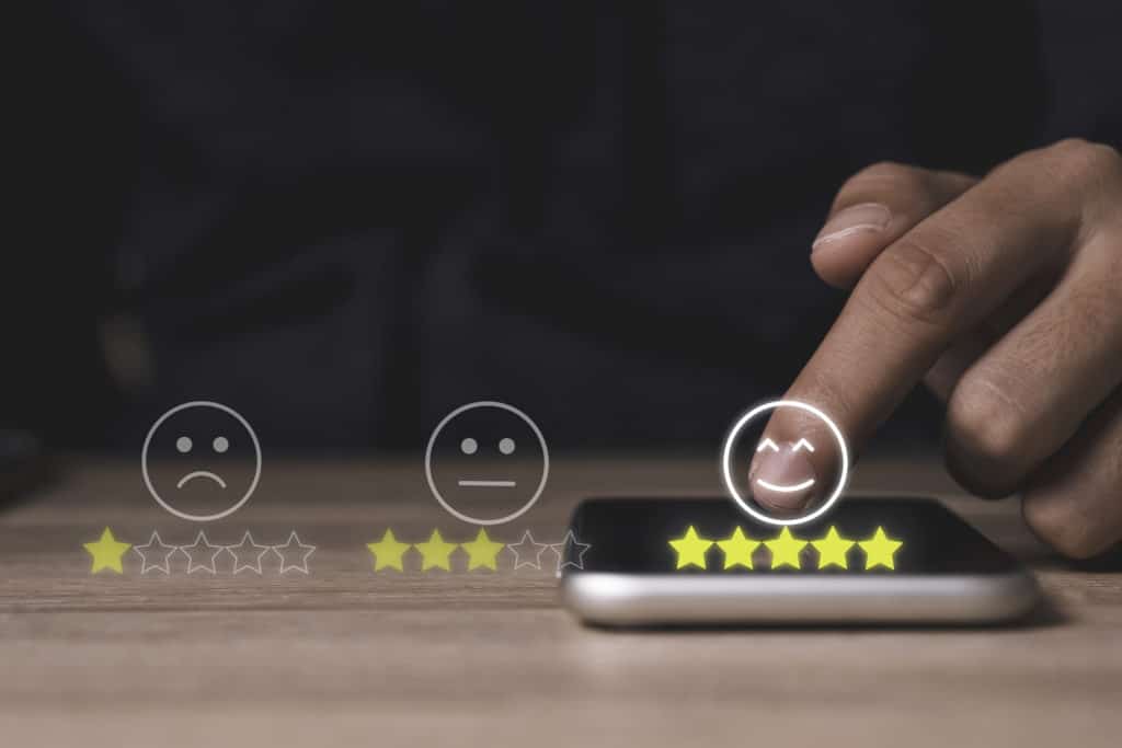 Hand touching a smart phone adding five yellow stars to for an online review