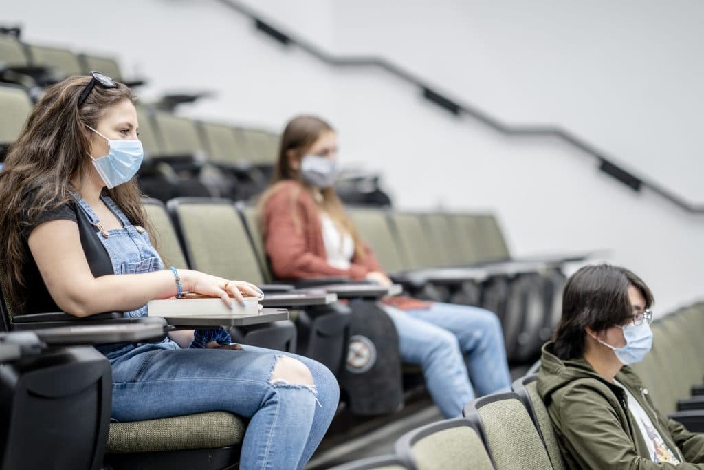 Students wearing masks and sitting socially distanced in a lecture hall