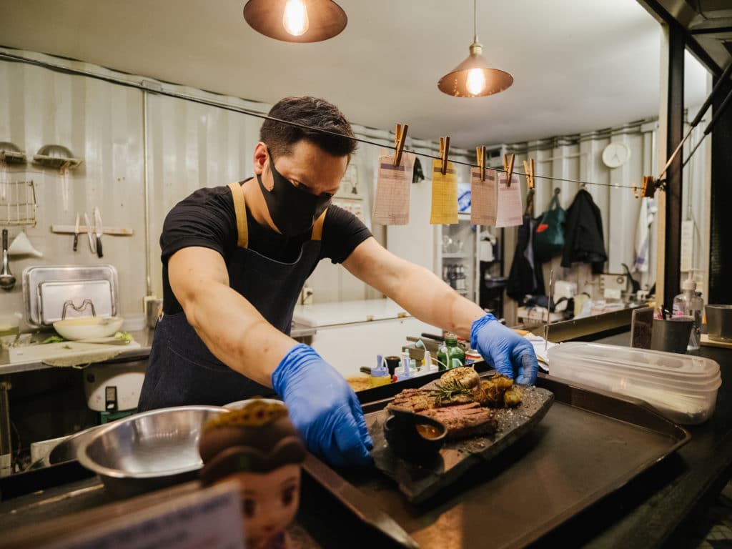 Ghost kitchen inside a shipping container with employee plating a dish