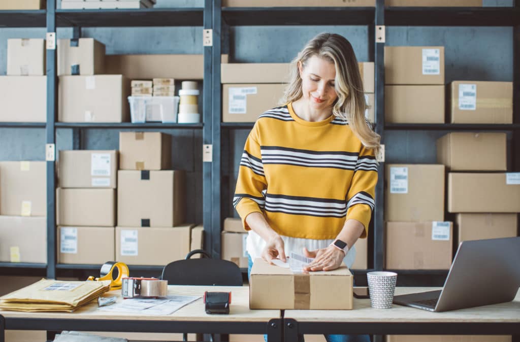 Female retail employee labeling packages for online orders