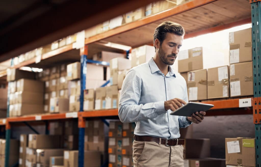 Male warehouse professional walking with a tablet for managing warehousing and inventory management