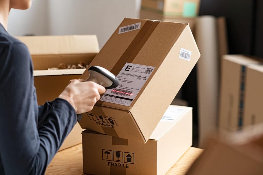 Hands of young woman scanning barcode on cardboard box delivery parcel