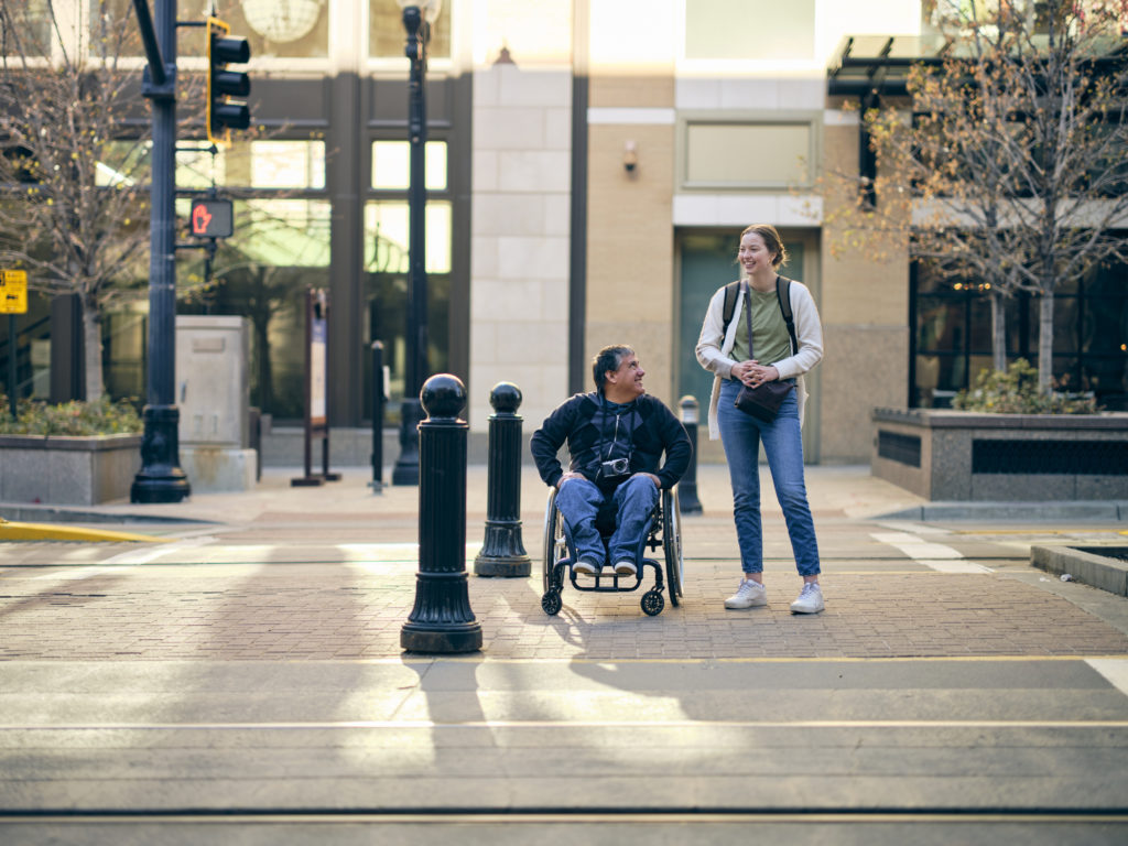 A man in a wheelchair with a young woman in a downtown area