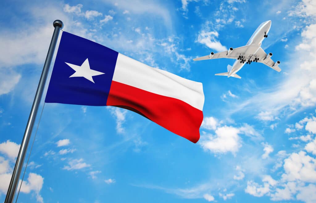 Texas flag blowing in the wind with an airplane flying behind