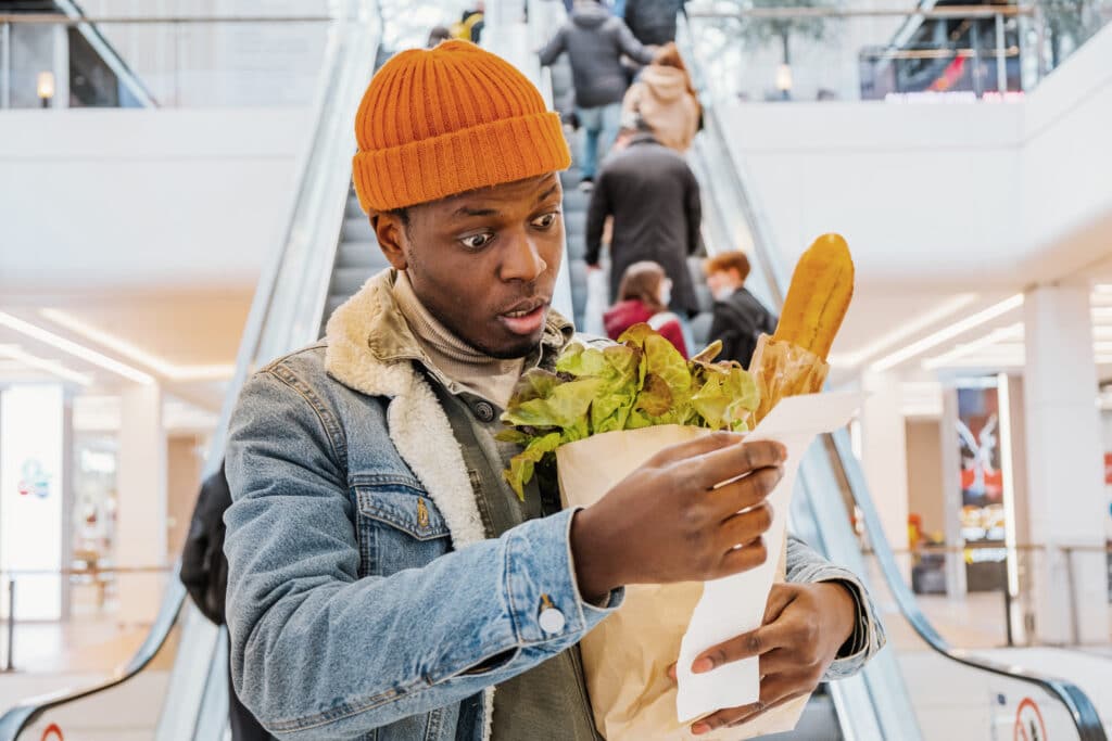 Man holding bag groceries reviewing a shopping receipt