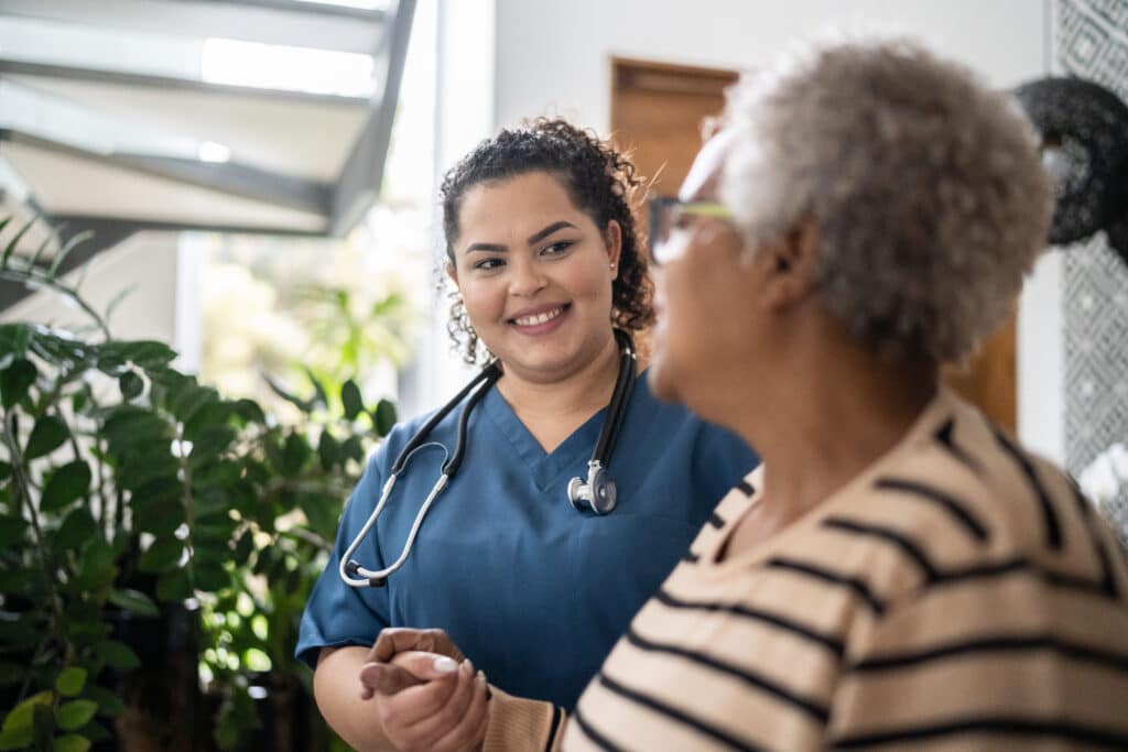 Young nurse guiding an older patient by the hand