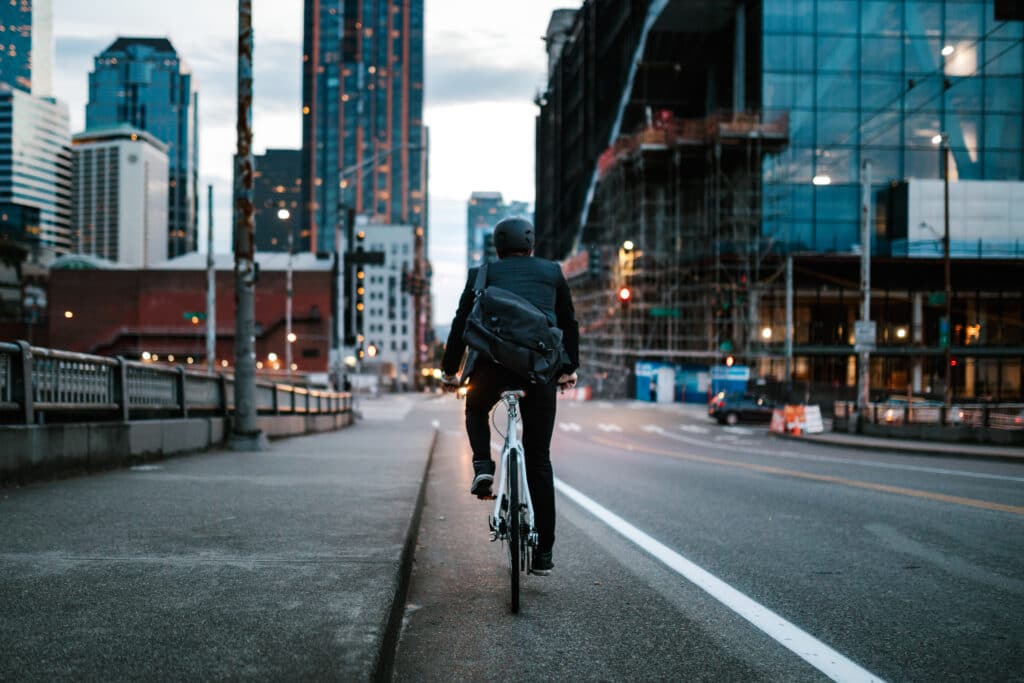 A younger business man wearing a blazer rides his bicycle through the city streets of Seattle, Washington