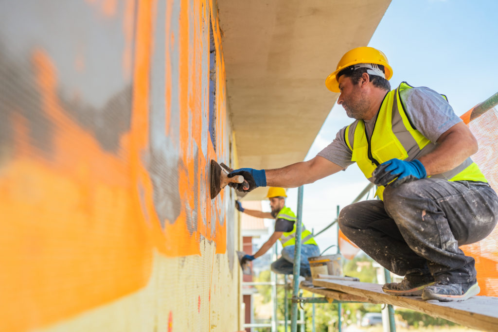 Construction workers on scaffolding applying plaster on a building