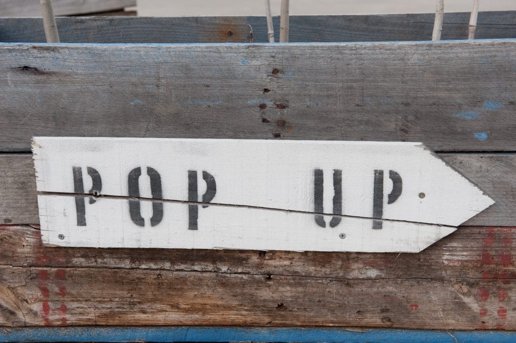 Image of a wood sign pointing toward a pop-up store rental