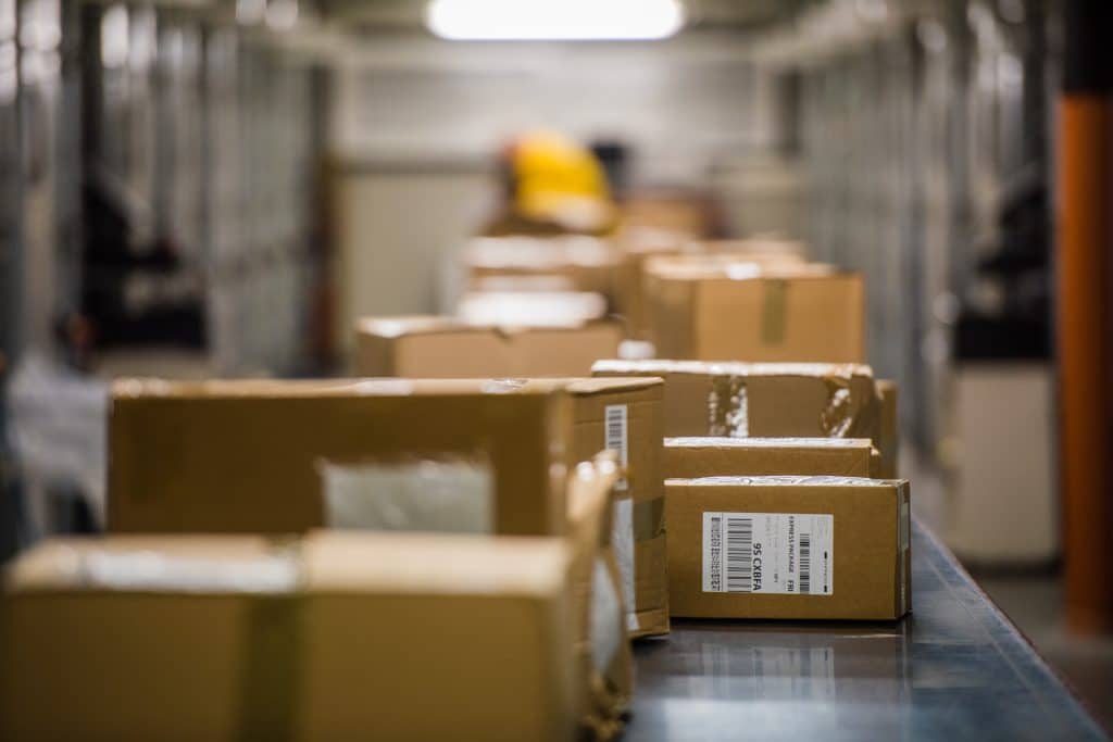 Boxes packed with holiday inventory moving on conveyer belt in warehouse.