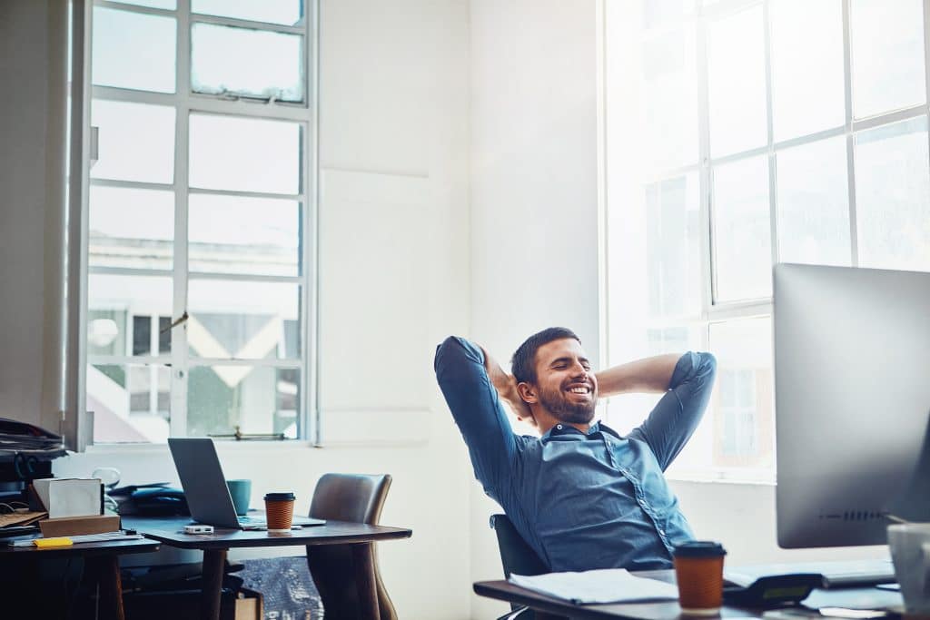 Male office employee sitting back and relaxing at his desk