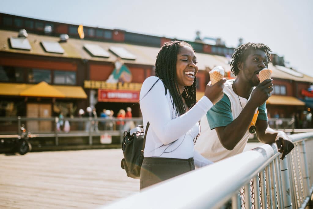 A cute young man and woman enjoy a tasty ice cream waffle cone on a sunny day in downtown Seattle