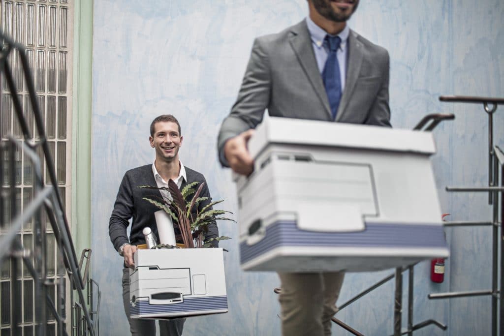 Relocating employees carry boxes out of the office