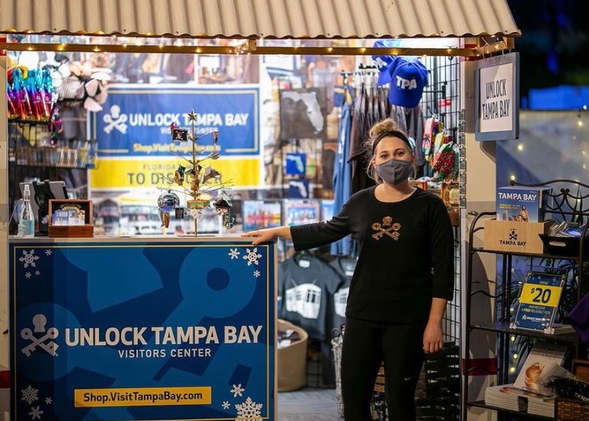 Woman standing at her outdoor popup shop PODS container at the Tampa Winter Village
