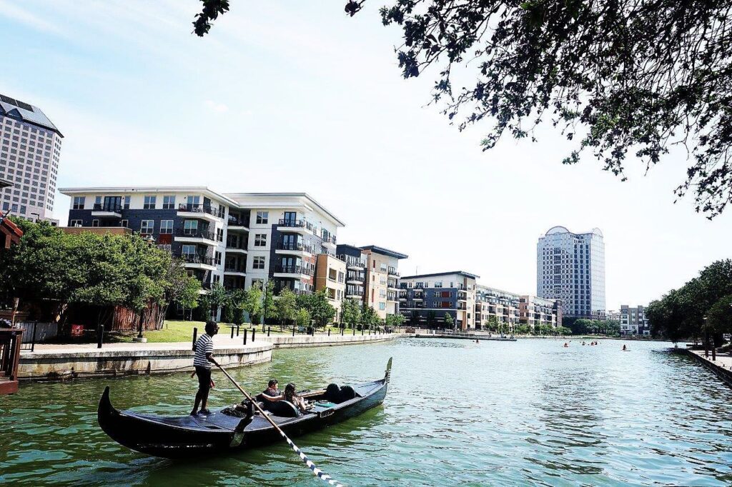 Man rowing couple on a gondola boat in a body of water in Irving