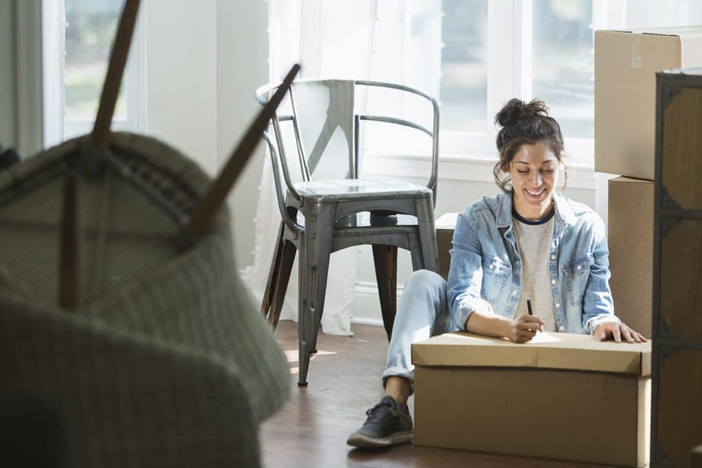 A women sitting on the ground packing boxes for commercial moving