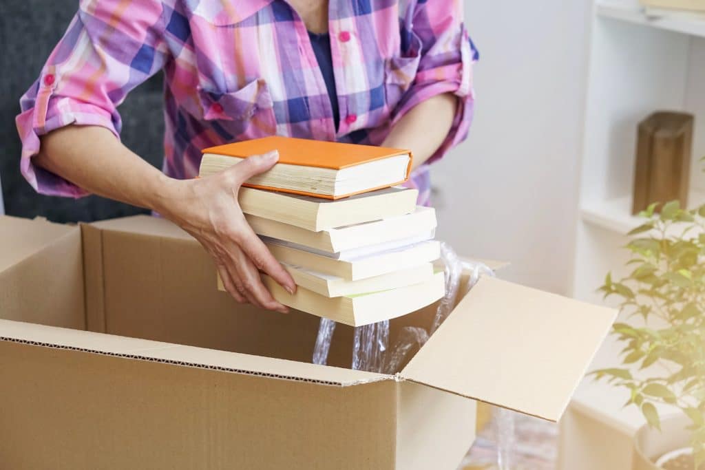 A woman packing into a moving box for relocating