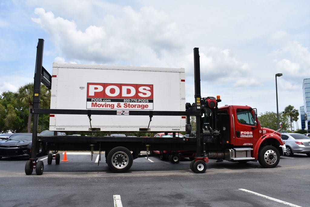 A PODS container being moved on a truck in a parking