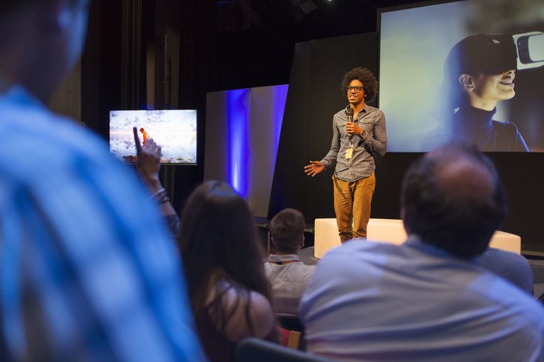 A man gives a presentation at a business conference on the benefits of a product drop