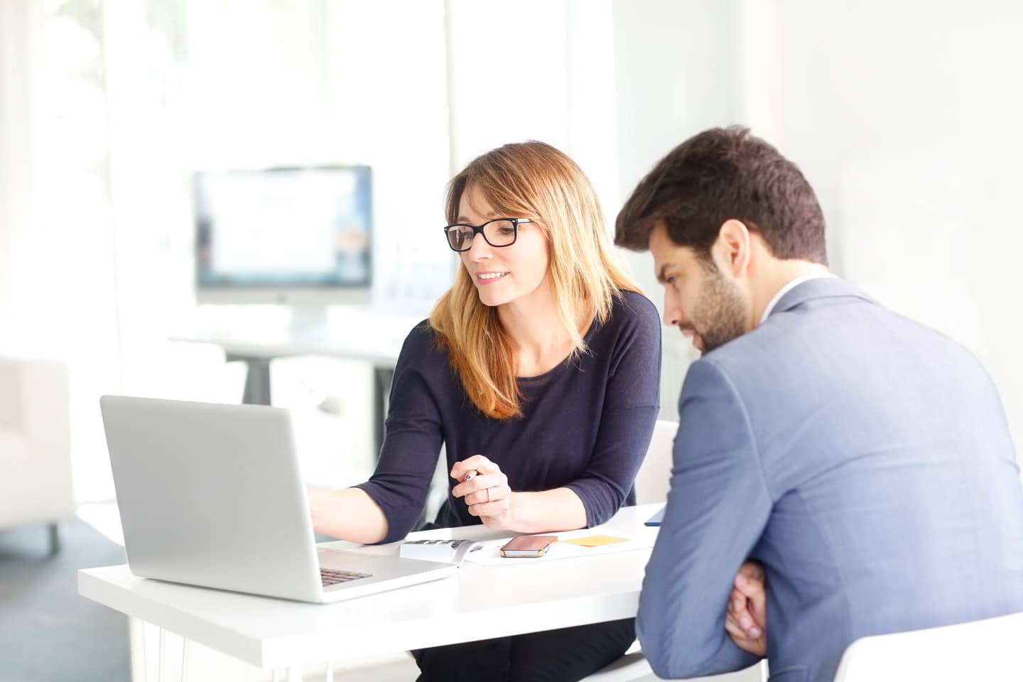 Two employees looking at a computer and discussing business inside an office